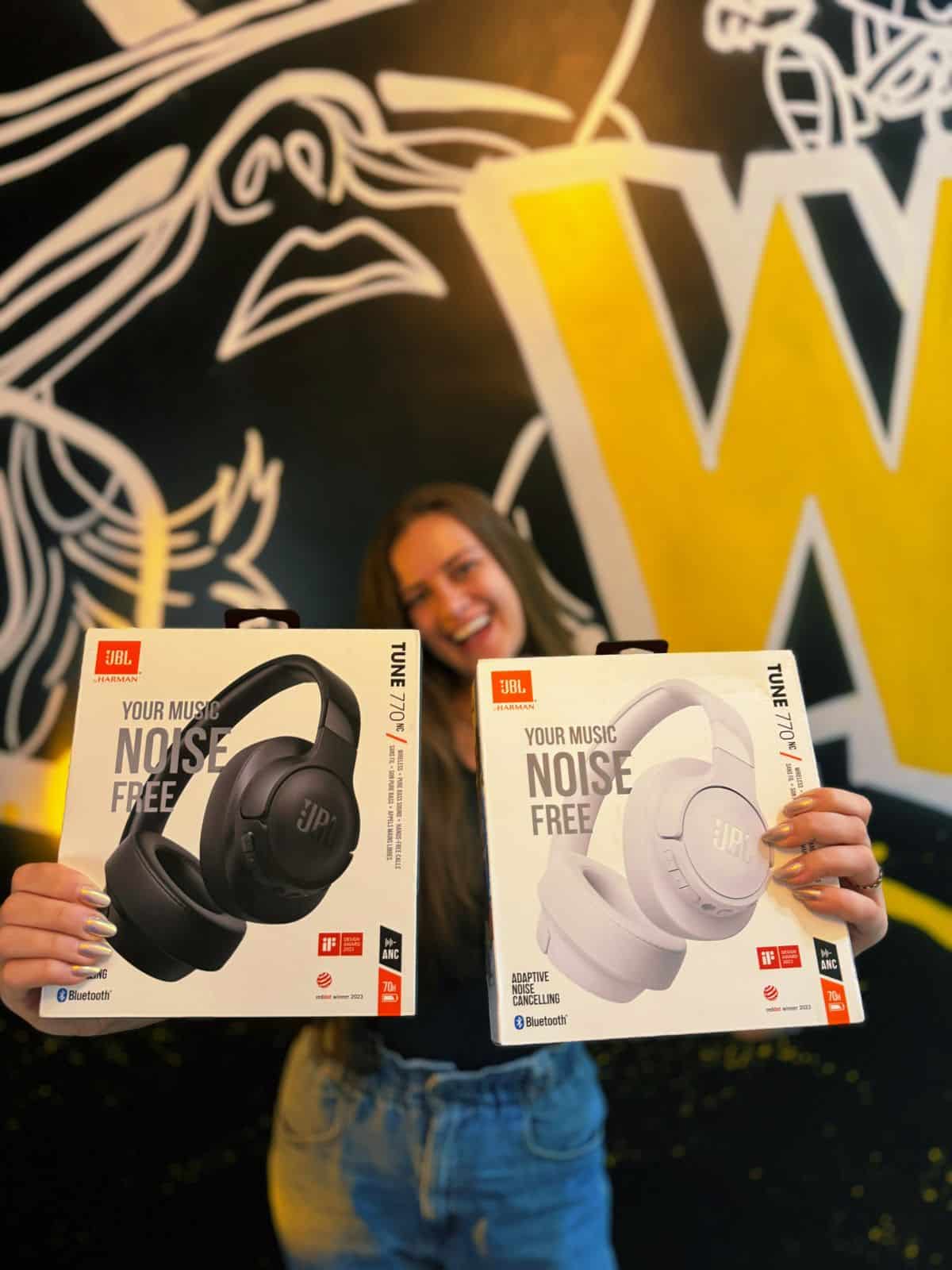 Quem somos Atendente da WANT IMPORT segurando fones de ouvido JBL originais